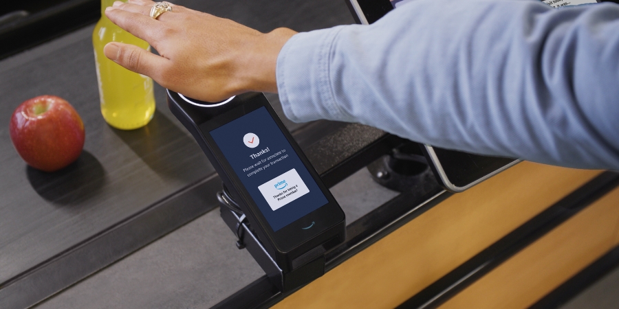 Person's palm over the Amazon One screen while checking out from Whole Foods