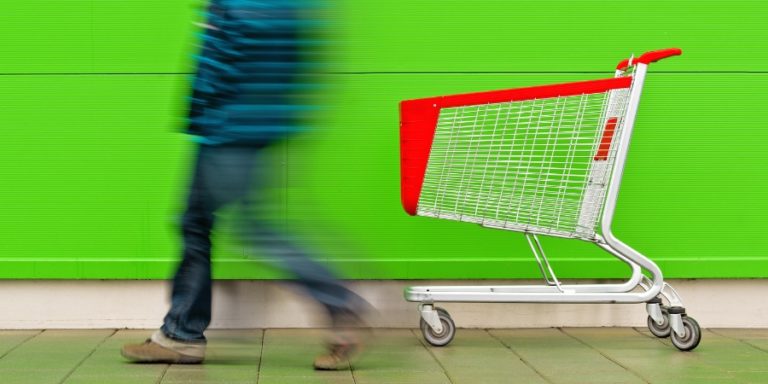 Blurred man walking away from a shopping cart on the sidewalk