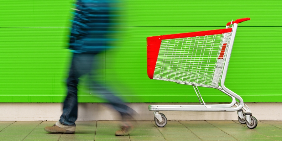 Blurred man walking away from a shopping cart on the sidewalk