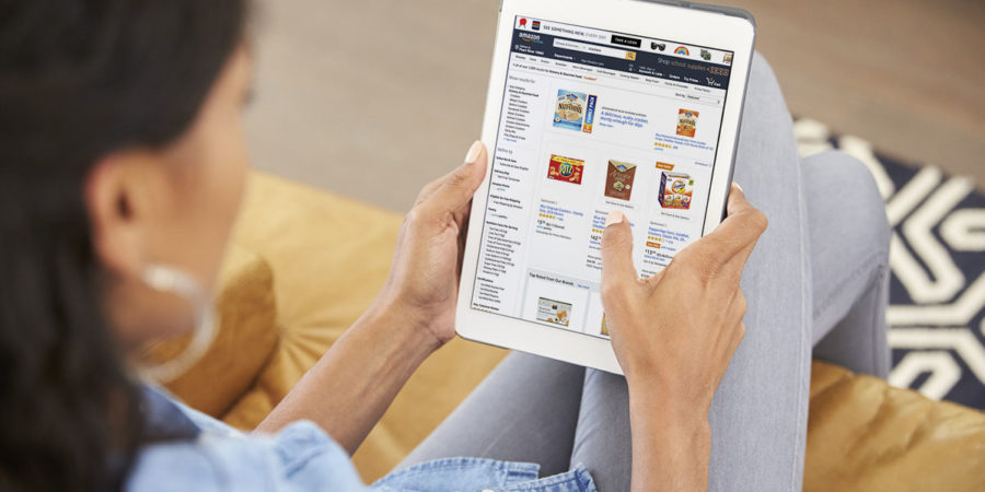 Woman Sitting On Sofa At Home Looking At Digital Tablet Woman Sitting On Sofa At Home Looking At Digital Tablet