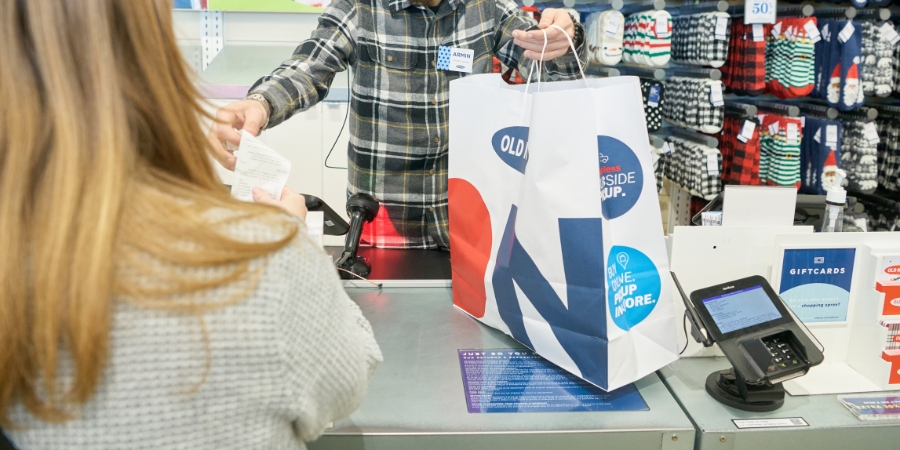 Person checking out at Old Navy, with the cashier handing her a bag and receipt